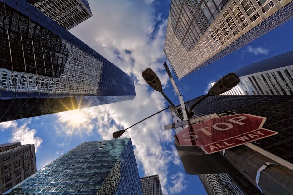Dynamic urban perspective of New York skyscrapers from below, capturing a stop sign.
